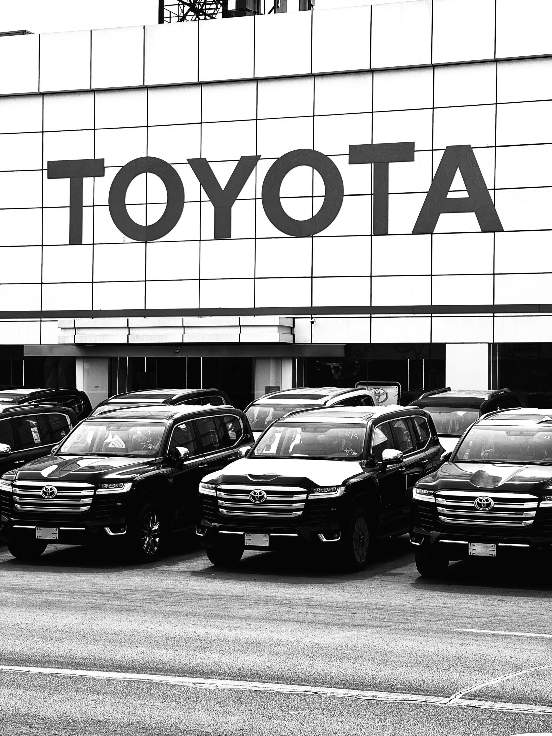 Home Black and white photo of Toyota SUVs parked at a dealership in an urban setting in Tianjin, China.